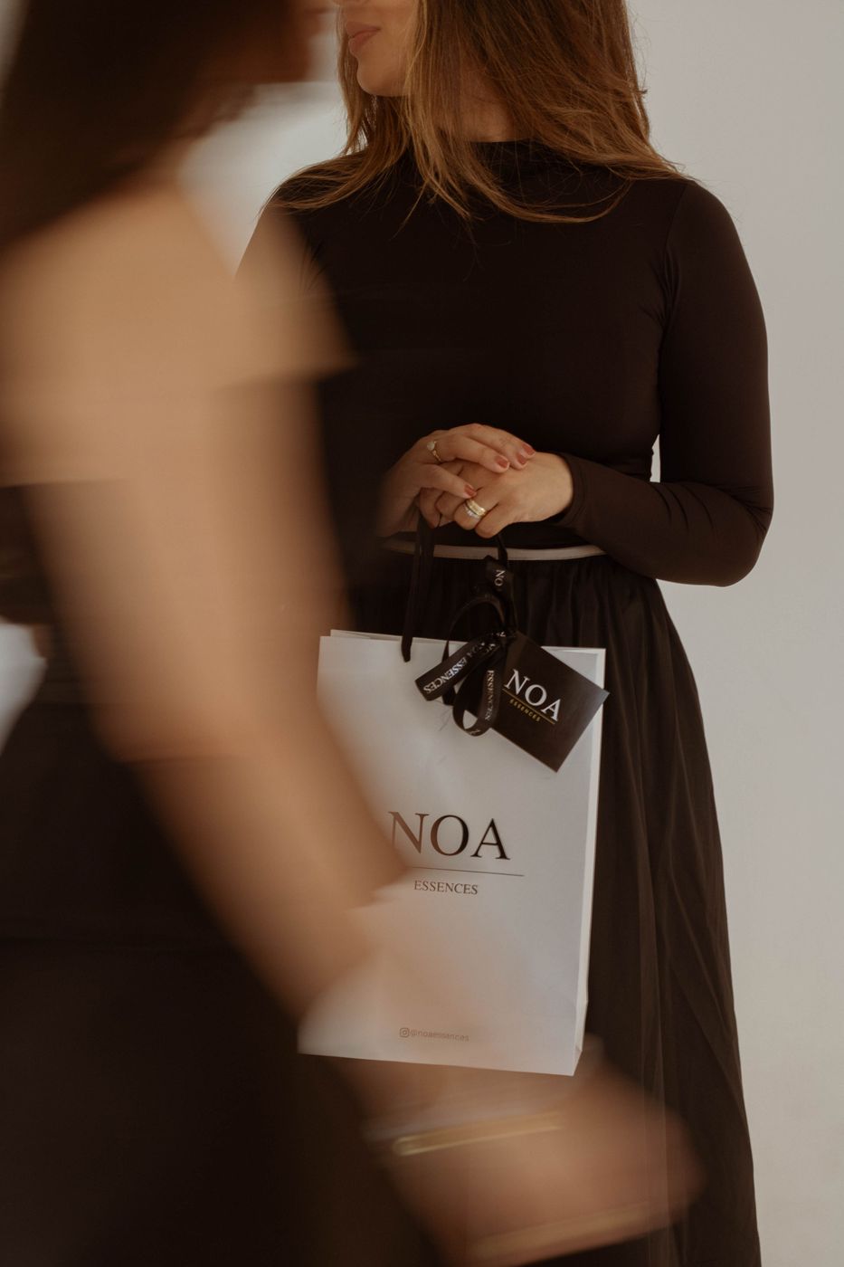Mulher de vestido preto segurando a sacola da Edição Flower